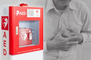 AED with ref m5070a battery with person in background holding chest.