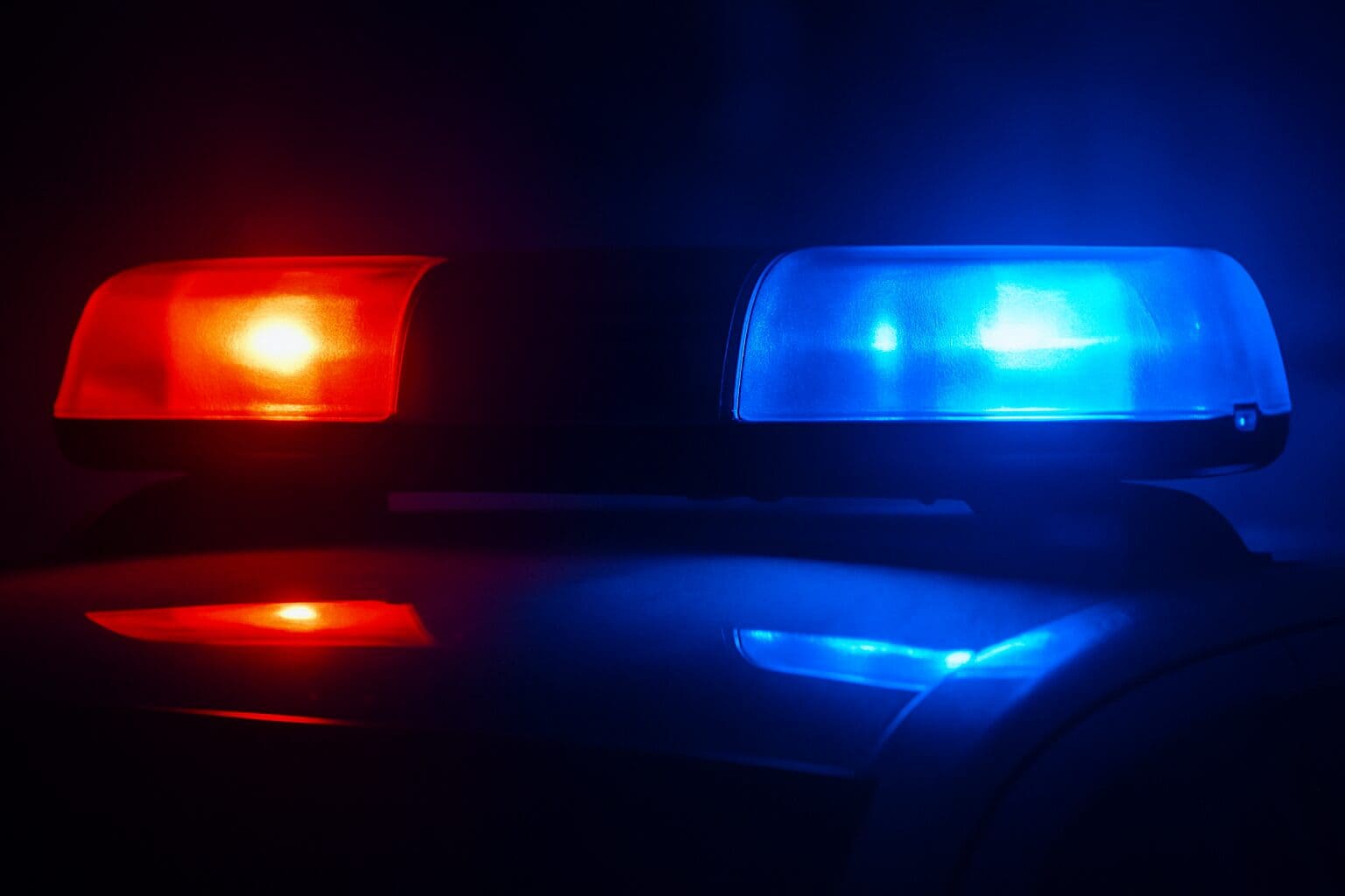 Close-up of flashing red and blue police lights on a patrol car at night