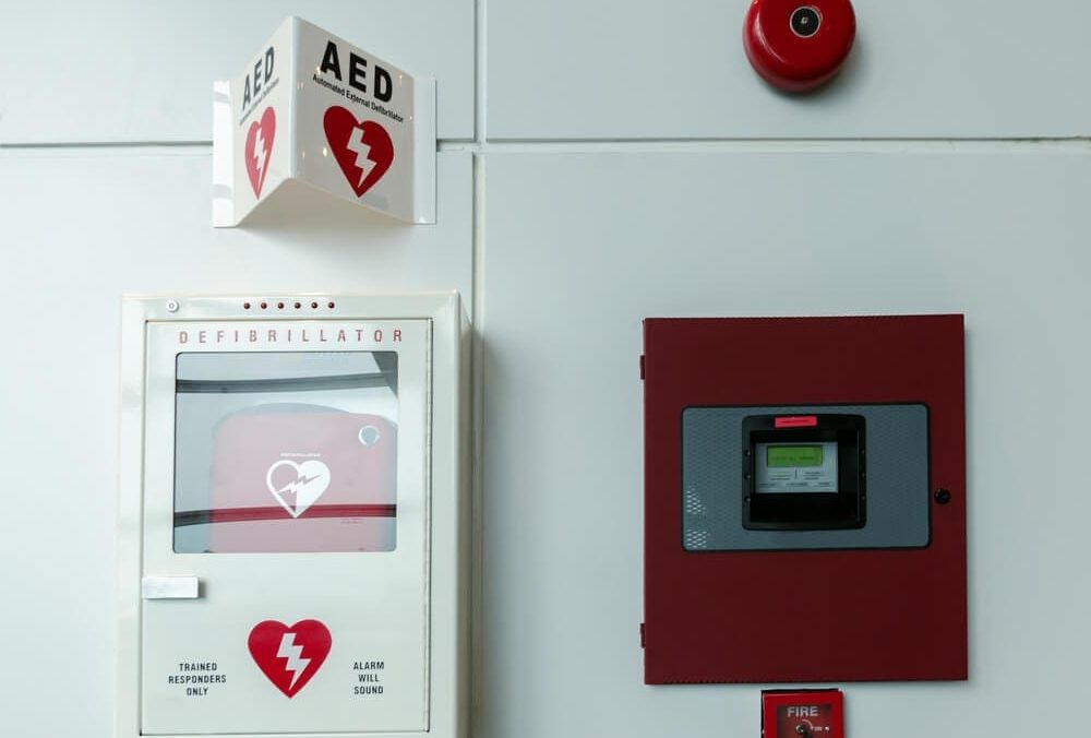 Portable automated external defibrillator (AED) and fire alarm system mounted on the wall in public restroom at airport.